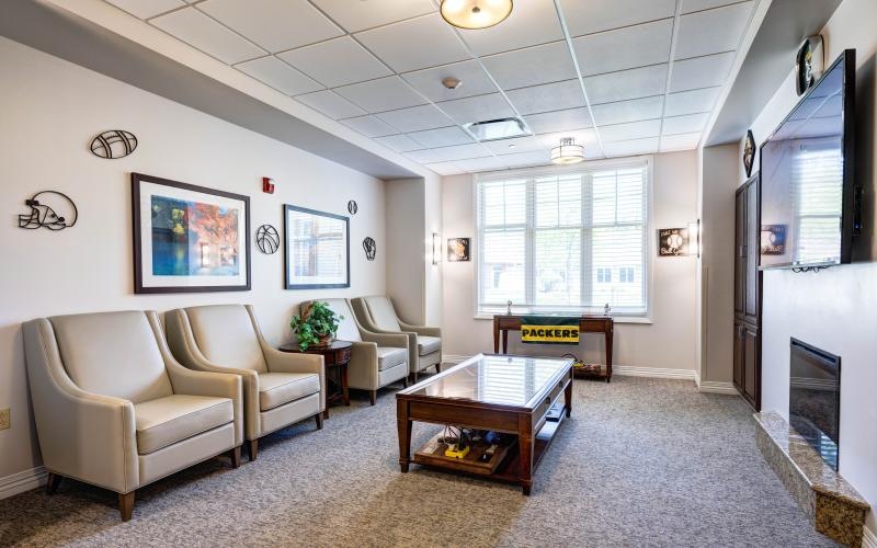 a room with white walls and a table with chairs and a tv