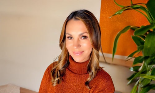 a woman in front of an orange and tan wall